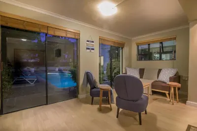 a living room with chairs and a table and a pool at Atlantic Bay Lodge in Cape Town