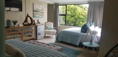 a bedroom with a bed and a chair and a window at Atlantic Bay Lodge in Cape Town
