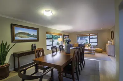 a dining room and living room with a table and chairs at Atlantic Bay Lodge in Cape Town