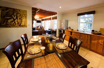a dining room with a wooden table and chairs at Le Manoir de Brendel in Franschhoek