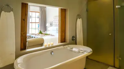 a bathroom with a tub and a large mirror at Zorgvliet Wines Country Lodge in Stellenbosch