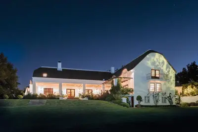 a large white house with a gambrel roof at Gemoedsrus Farm in Stellenbosch
