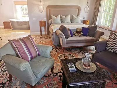 a bedroom with a bed and two chairs and a teddy bear at Gemoedsrus Farm in Stellenbosch
