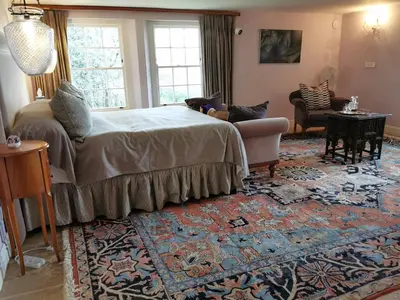 a bedroom with a bed and a couch and a rug at Gemoedsrus Farm in Stellenbosch