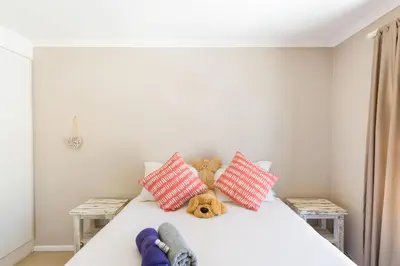 a bedroom with a bed with a teddy bear and pillows at Nansen Place in Cape Town