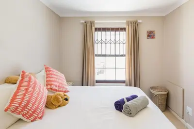 a bedroom with a white bed with stuffed animals on it at Nansen Place in Cape Town