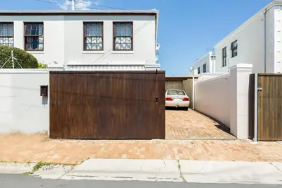 a house with a wooden gate in front of a driveway at Nansen Place in Cape Town