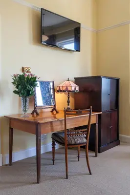 a wooden desk with a chair and a table with a mirror at Medindi Manor in Cape Town