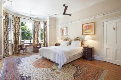 a bedroom with a large bed and a dining room at Medindi Manor in Cape Town