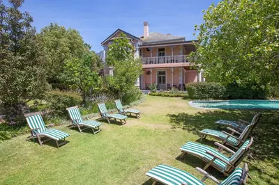 a group of lawn chairs in front of a house at Medindi Manor in Cape Town
