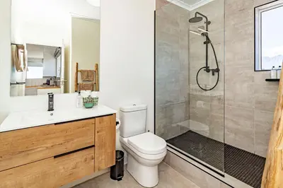 a bathroom with a shower and a toilet and a sink at Morgen Guesthouse Somerset West in Somerset West