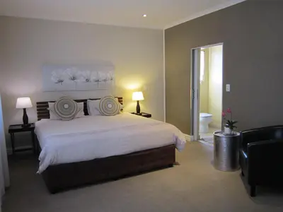a bedroom with a large white bed and a bathroom at La Roche Guest House in Cape Town
