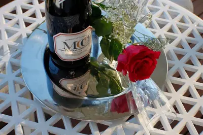 a bottle of wine on a table with a vase of flowers at Keret Accommodation in Bellville