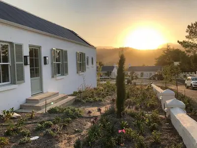 a house with the sunset in the background at La Cotte Orchard Cottages in Franschhoek