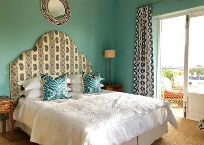 a bedroom with a large white bed with blue walls at La Cotte Orchard Cottages in Franschhoek