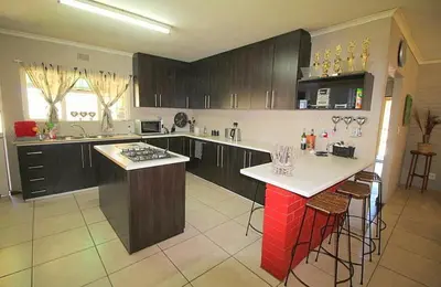a kitchen with brown cabinets and a white counter top at Cape Pine Guest House in Kuilsrivier