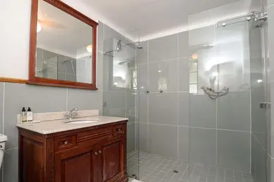 a bathroom with a shower with a sink and a mirror at Dark Chocolate Guest House in Durbanville