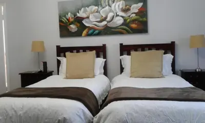 two beds in a room with a painting on the wall at Dark Chocolate Guest House in Durbanville