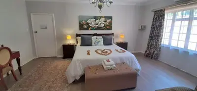 a bedroom with a large white bed and a table at Dark Chocolate Guest House in Durbanville