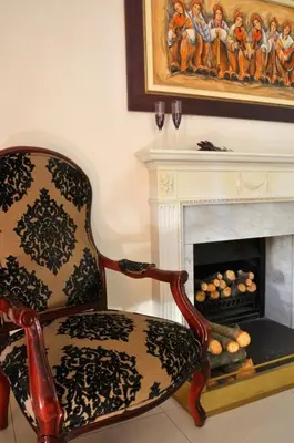 a chair in a living room with a fireplace at Dark Chocolate Guest House in Durbanville