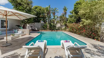 a swimming pool with two chairs and an umbrella at Sea Breeze Guest House in Bloubergstrand