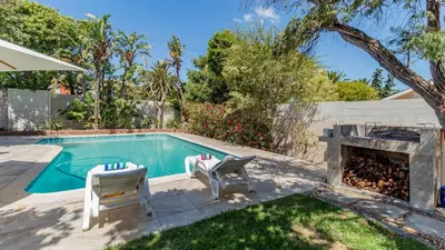a swimming pool with two chairs and a table at Sea Breeze Guest House in Bloubergstrand