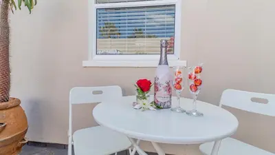 a white table with a bottle of wine and two glasses at Sea Breeze Guest House in Bloubergstrand