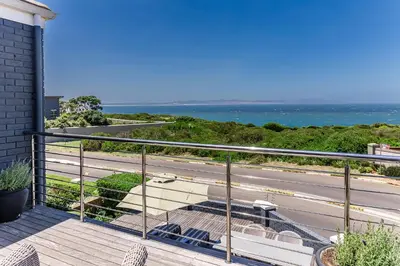 a balcony with a view of a road and the ocean at The Whale's Tale Guesthouse in Hermanus
