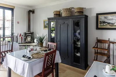 a dining room with a table and a black cabinet at The Whale's Tale Guesthouse in Hermanus
