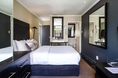 a bedroom with a large white bed and a mirror at Life & Leisure Boutique Guesthouse in Stellenbosch