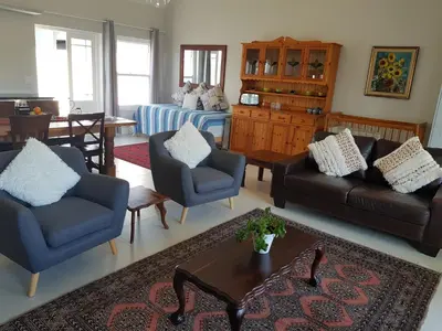 a living room with a couch and chairs and a table at Coral Tree in Hermanus
