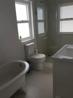 a bathroom with a toilet and a tub and a sink at Coral Tree in Hermanus