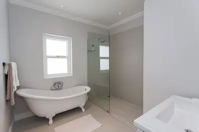 a white bathroom with a tub and a sink at Coral Tree in Hermanus
