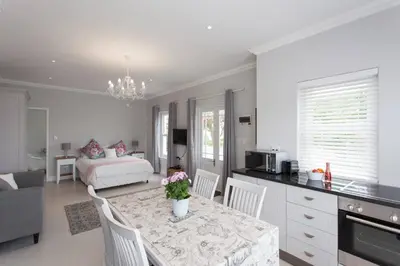 a kitchen and living room with a table and a bed at Coral Tree in Hermanus