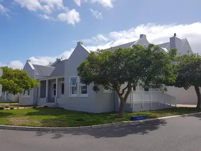 a white house with a tree in front of it at Coral Tree in Hermanus