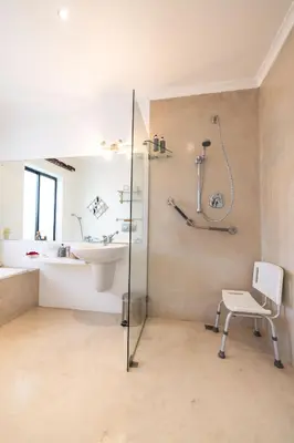 a bathroom with a shower and a sink and a chair at Cape Pillars Boutique Hotel in Durbanville