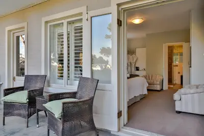 a room with chairs and a bed and a window at Hermanus Lodge on the Green - Solar Power in Hermanus