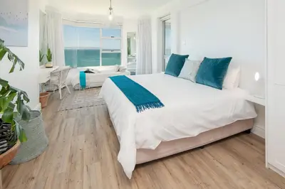 a bedroom with a large white bed with blue pillows at Bayview Bliss in Hermanus