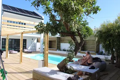 a man sitting on a couch next to a swimming pool at Whale Rock Luxury Lodge in Hermanus