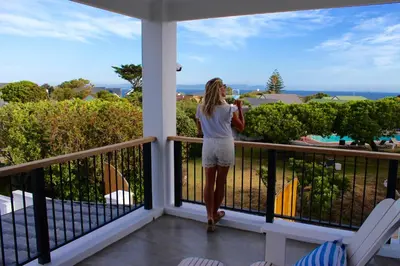 a woman standing on a balcony looking at the ocean at Whale Rock Luxury Lodge in Hermanus