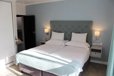 a bedroom with a large bed with white sheets and pillows at Whale Rock Luxury Lodge in Hermanus