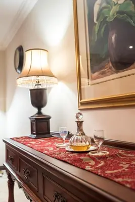 a table with wine glasses and a lamp on it at Blaauwheim Guest House in Somerset West