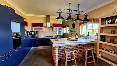 a kitchen with blue cabinets and a brick island with stools at Sandmartins in Suider-Paarl