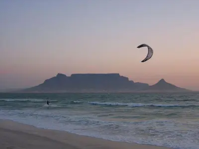 a person flying a kite in the ocean on the beach at Elements Cape Town in Table View