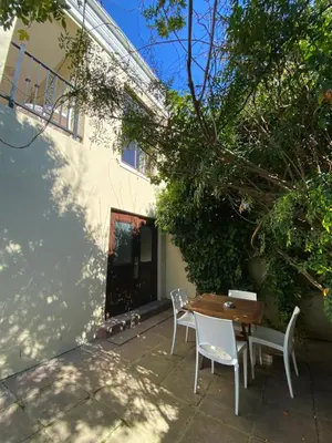 a patio with a wooden table and chairs next to a building at @Leisure Guest Suite in Stellenbosch