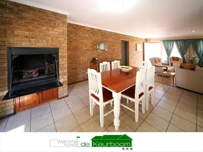 a living room with a wooden table and a fireplace at De Keurboom Guesthouse in Kuilsrivier