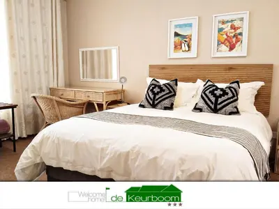 a bedroom with a large bed with white sheets and pillows at De Keurboom Guesthouse in Kuilsrivier