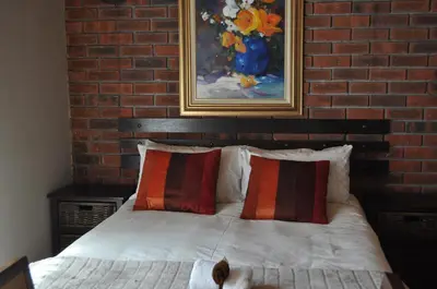 a bedroom with a bed with a brick wall at Pelican Place Guest Cottages in Durbanville