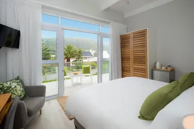 a bedroom with a white bed and a large window at Bamboo Guest House in Hermanus