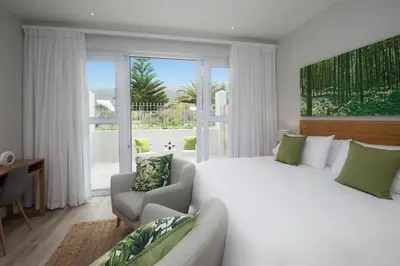 a bedroom with a large bed and a living room at Bamboo Guest House in Hermanus